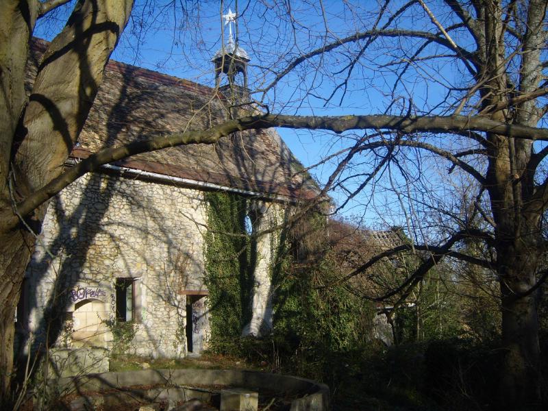 Chapelle en mauvaise état en hiver derrière les arbres.