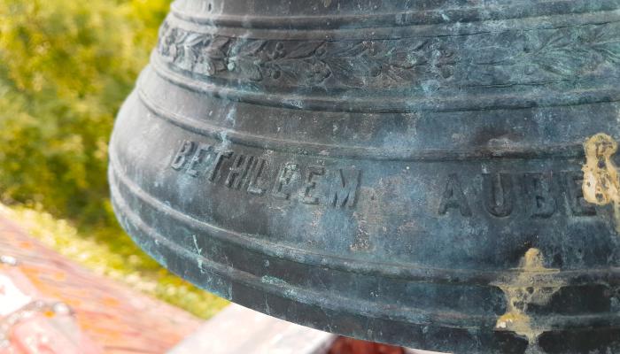 Des écritures sur la cloche de la chapelle. La cloche a été donnée en 1897 par un certain P. Peck